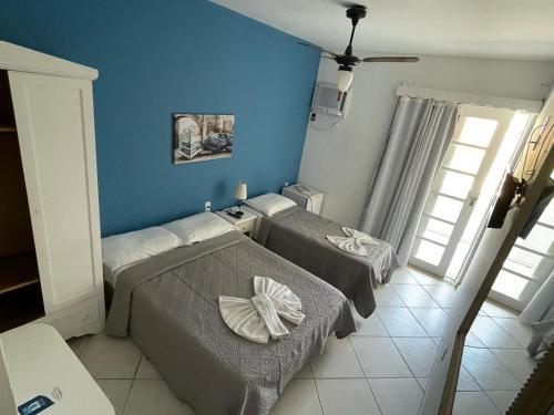 a bedroom with two beds and a blue wall at Pousada Kopenhagen Beach in Cabo Frio