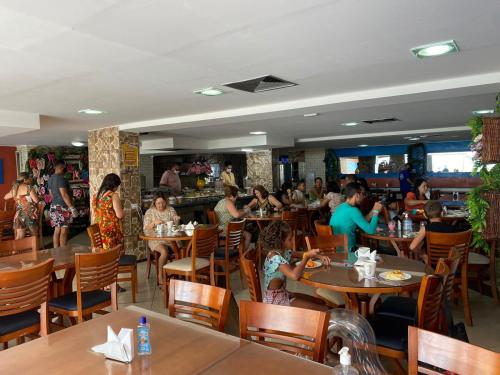 a group of people sitting at tables in a restaurant at Beira Mar Imperial Flat 612 in João Pessoa