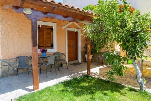 a patio with a table and chairs and a tree at Pink house in Drepana