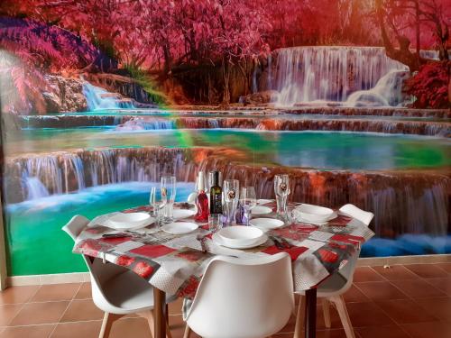 a table with chairs and a painting of a waterfall at Maria's - Parking Area, no ZTL, close Train Station and Beach in Cefalù