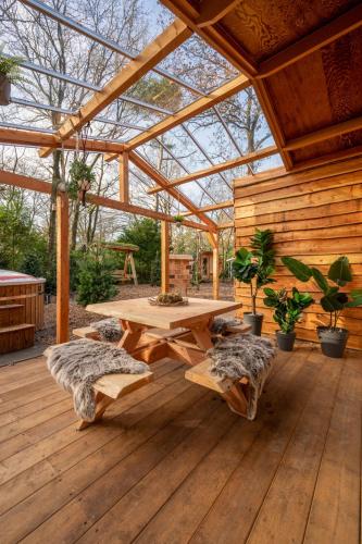 a wooden patio with a wooden table and benches at ZEN-Bungalow NO 3 met sauna en hottub in Rheezerveen