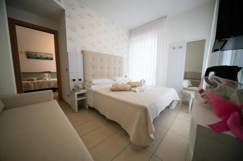 a white bedroom with a bed and a mirror at Hotel ABC in Riccione