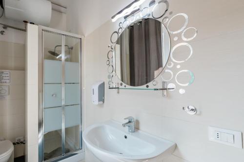 bagno bianco con lavandino e specchio di BG Stay a Bergamo