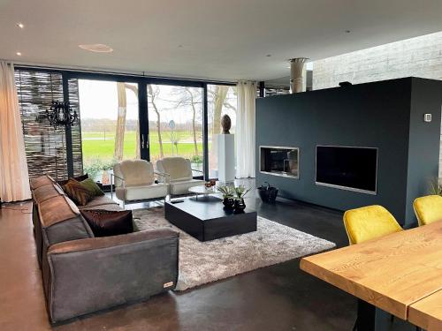 a living room with a couch and chairs and a tv at Betonnen Boshuis in Oosterhout