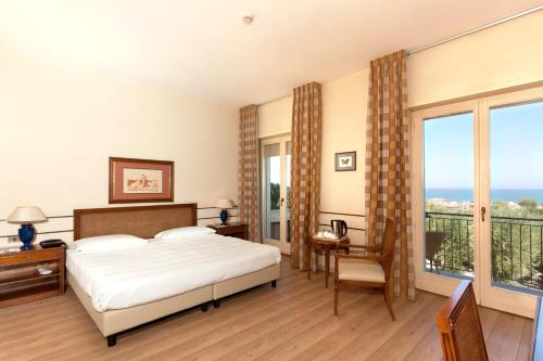 a bedroom with a bed and a balcony with the ocean at Villa Maria Hotel & SPA in Francavilla al Mare