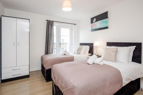 Impeccable 2-Bed Apartment in Romford في رومفورد: سريرين في غرفة بجدران بيضاء