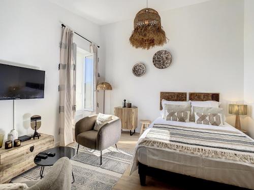 - une chambre avec un lit, une chaise et une télévision dans l'établissement Le Papillon de Saint-Tropez, à Saint-Tropez