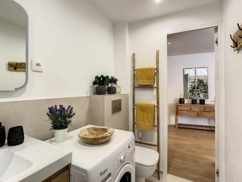 La salle de bains blanche est pourvue d'un lavabo et d'un lave-linge. dans l'établissement Le Papillon de Saint-Tropez, à Saint-Tropez