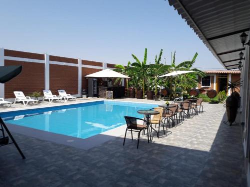 a swimming pool with chairs and a table and umbrella at Huacachina Desert House in Ica