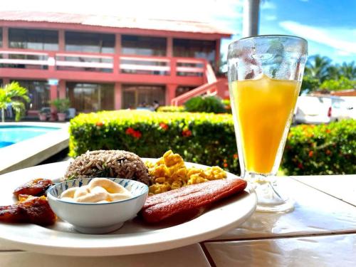 a plate of food and a glass of orange juice at Hotel La Roca del Mar in Puntarenas