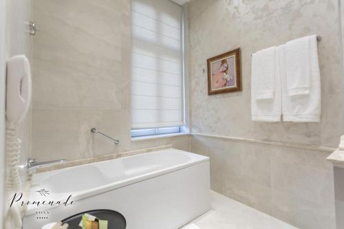 a white bathroom with a tub and a window at Villa Promenade in Burgas City