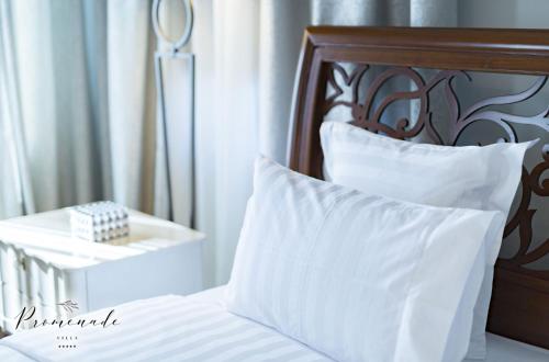 a bed with white pillows and a wooden headboard at Villa Promenade in Burgas City