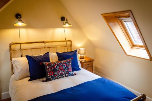 Un dormitorio con una cama con almohadas azules y una ventana en Kirk Wynd Cottage, en Kirriemuir