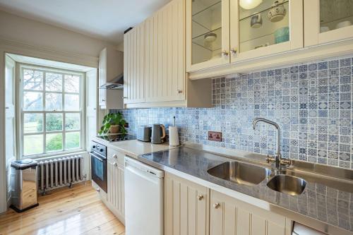 una cocina con armarios blancos y fregadero en Stewart Apartment en Newton Stewart