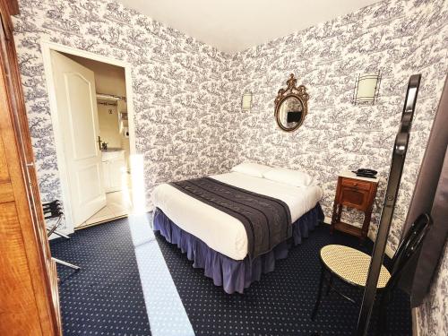 a small room with a bed and a mirror at Hotel De La Poste in Langres