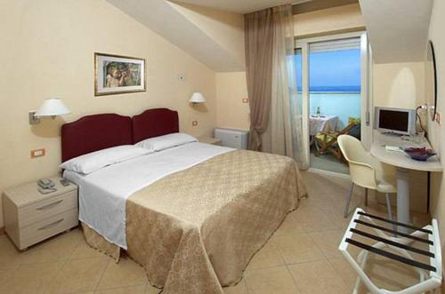 sypialnia z dużym łóżkiem i biurkiem z komputerem w obiekcie Hotel Souvenir w mieście Lido di Savio