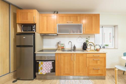 a kitchen with wooden cabinets and a stainless steel refrigerator at Aguda Beach Porto, Slow Travel Houses in Vila Nova de Gaia