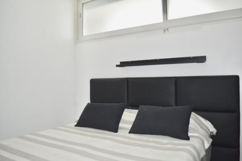 - un lit avec une tête de lit noire et 2 oreillers dans l'établissement LE PEARL - La grande motte 1er ligne vue mer - climatisation et parking, à La Grande Motte