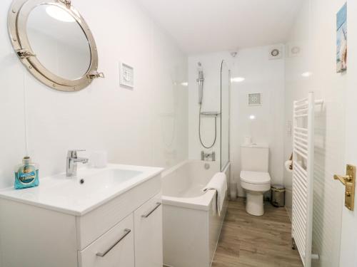 a white bathroom with a sink and a toilet at Seaspray Cottage in Buckie