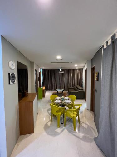 a living room with a table and yellow chairs at Vortex Suites Klcc by Rit Villa in Kuala Lumpur