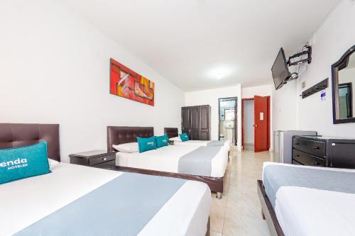 um quarto de hotel com três camas e uma televisão em Ayenda Imperio la 16 em Pereira