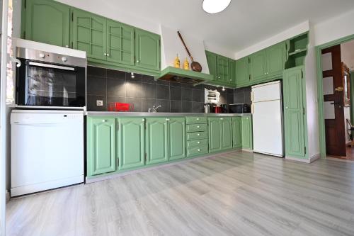 une cuisine verte avec des appareils électroménagers blancs et des armoires vertes dans l'établissement Magnifique 3 pièces, à Port-Vendres