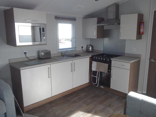 een keuken met witte kasten, een wastafel en een fornuis bij 54 Apple Grove in Exmouth