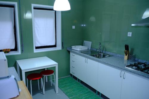 a green kitchen with a sink and two red stools at Apartamento Alegria in Arouca