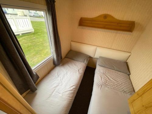 a small room with two beds and a window at Reighton Sands 1 in Filey