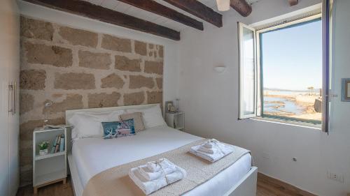 1 dormitorio con cama blanca y pared de ladrillo en Welcomely - Waterfront home a balcony on the sea, en Alghero