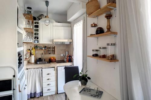 uma pequena cozinha com armários brancos e uma mesa em HENRI CAMILLE REAL ESTATE - CARNOT - Nice studio 8min Palais em Cannes