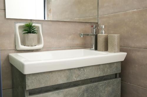 a white sink in a bathroom with a plant at Luxury Apartments Christos in Gouvia