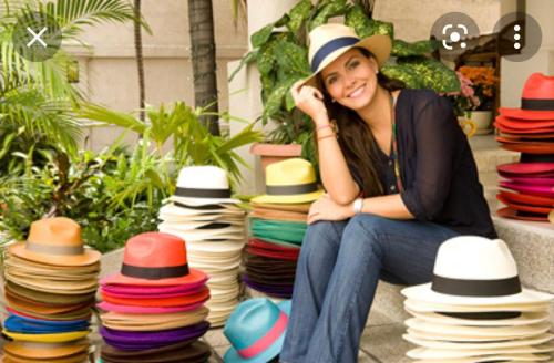 a woman sitting on the ground next to a pile of hats at Los Tamarindos Posadamanabita in Portoviejo