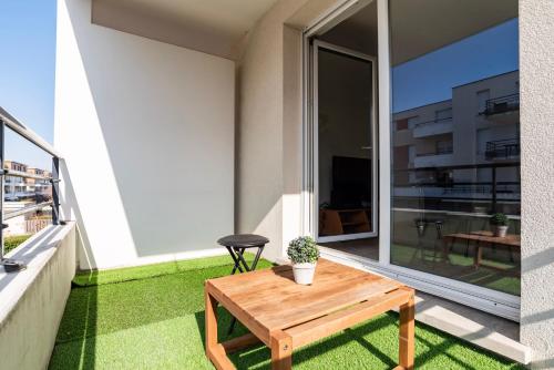 d'une terrasse avec une table en bois sur un balcon. dans l'établissement Le Zénith - Parking privé & WIFI - 5 min Zénith de Strasbourg, à Strasbourg