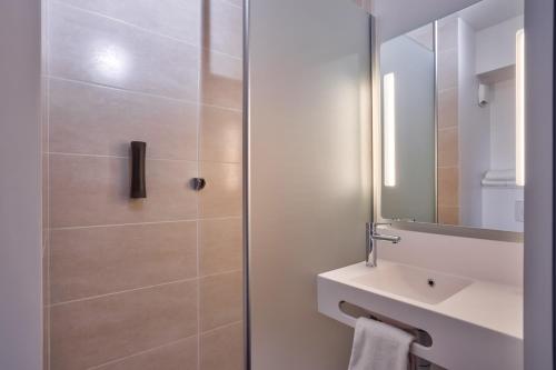 a bathroom with a shower and a sink and a mirror at B&B HOTEL Paris Créteil in Créteil