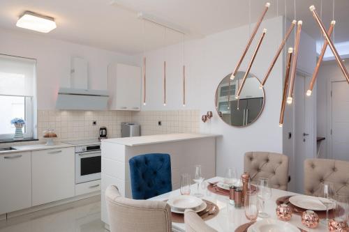 a white kitchen with a dining table and chairs at Elais Luxury Residence in Podstrana