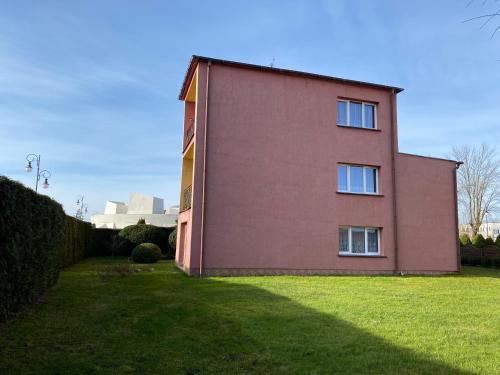 a red building with a grassy yard in front of it at Willa Malwa in Rewal
