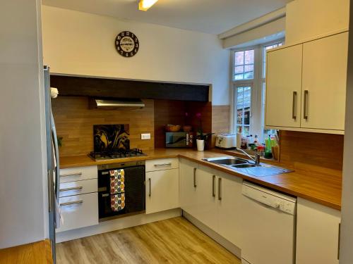 a kitchen with white cabinets and a clock on the wall at Jasmine House in Lutterworth