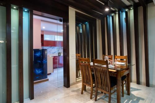 Home2 Suites and Service Apartments, Mumbai Airport في مومباي: غرفة طعام مع طاولة وكراسي خشبية