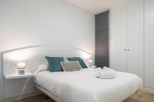 1 dormitorio con 1 cama blanca grande con almohadas azules en Estudio Las Navas, en Cádiz