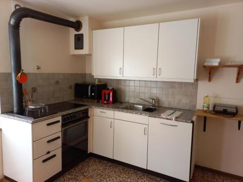 eine Küche mit weißen Schränken und einem Waschbecken in der Unterkunft Casa Vacanza Ponte Aino in Poschiavo