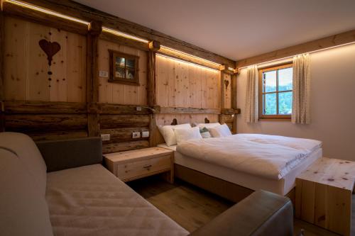 een slaapkamer met 2 bedden en een bank. bij Agriturismo Malga Piè in Soraga