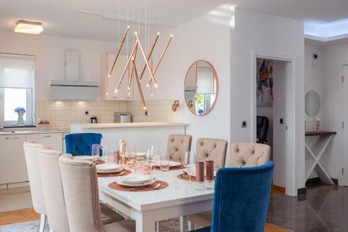 a dining room with a white table and blue chairs at Elais Luxury Residence in Podstrana