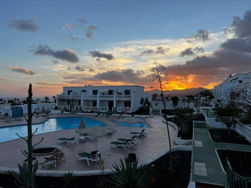 een resort met een zwembad met een zonsondergang op de achtergrond bij Casa Zen, 1 bedroom apartment on complex with pool, Puerto del Carmen in Puerto del Carmen