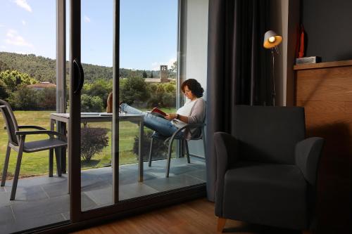 a woman sitting at a table looking at a book at Hotel Món Sant Benet in Sant Fruitos de Bages