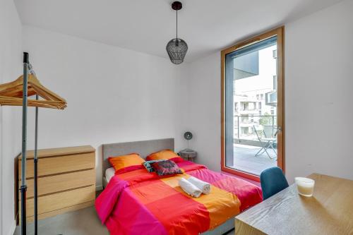 een slaapkamer met een bed met kleurrijke lakens en een tafel bij Chic and spacious apart southern Paris in Massy