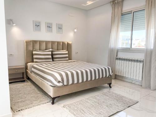 een slaapkamer met een bed met een zwart-wit dekbed bij Cosy Apartment in La Marsa - 2 bed 1 Bath in La Marsa