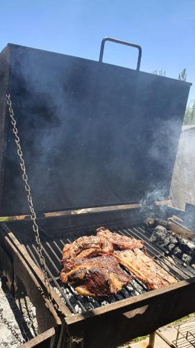 a steak cooking on a grill with a chain at Rancho Por Fin in Barreal