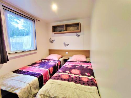 Duas camas num quarto com uma janela em Bungalow de 2 chambres avec piscine partagee terrasse amenagee et wifi a Saint Jean de Monts a 1 km de la plage em Saint-Jean-de-Monts