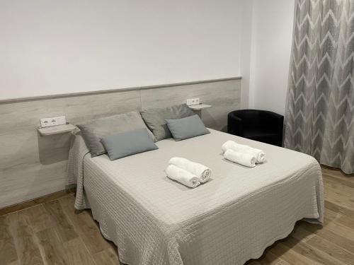 Una cama blanca con dos toallas encima. en alojamiento saturno1 en Conil de la Frontera